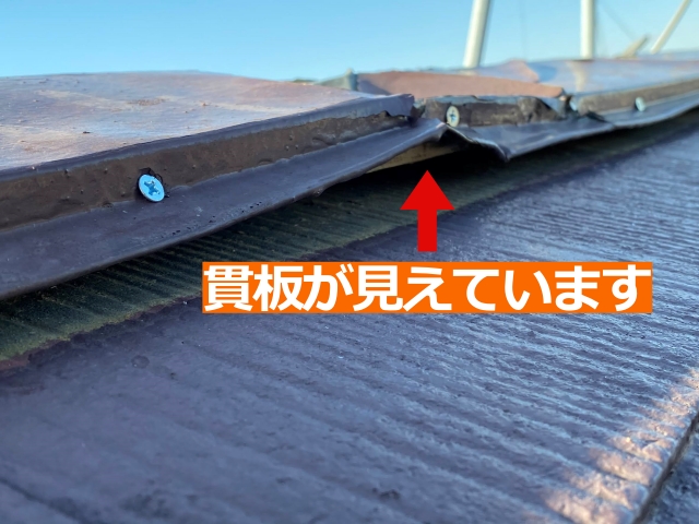 歪んだ棟板金の下から貫板が露出